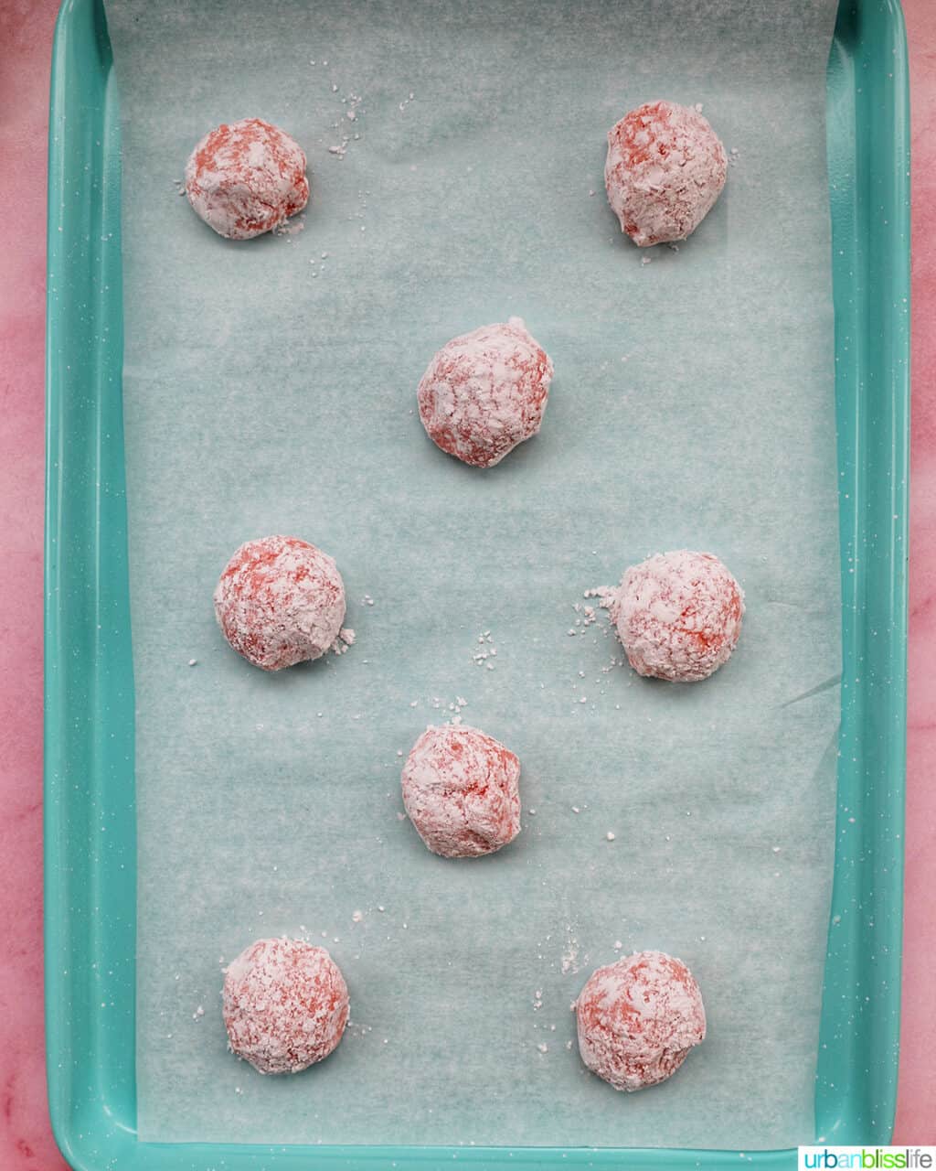 rolled strawberry crinkle cookie balls on baking sheet
