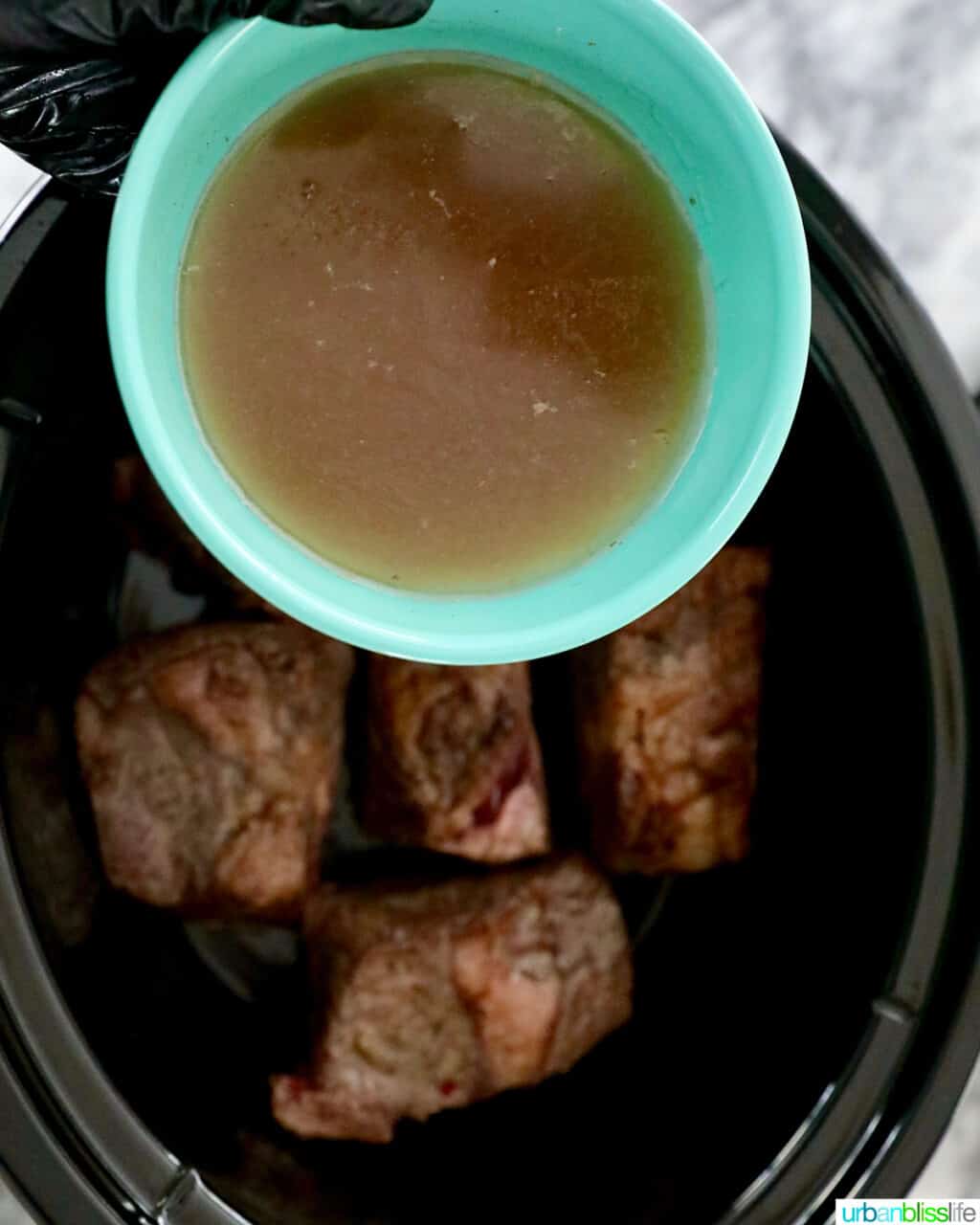 adding broth to slow cooker