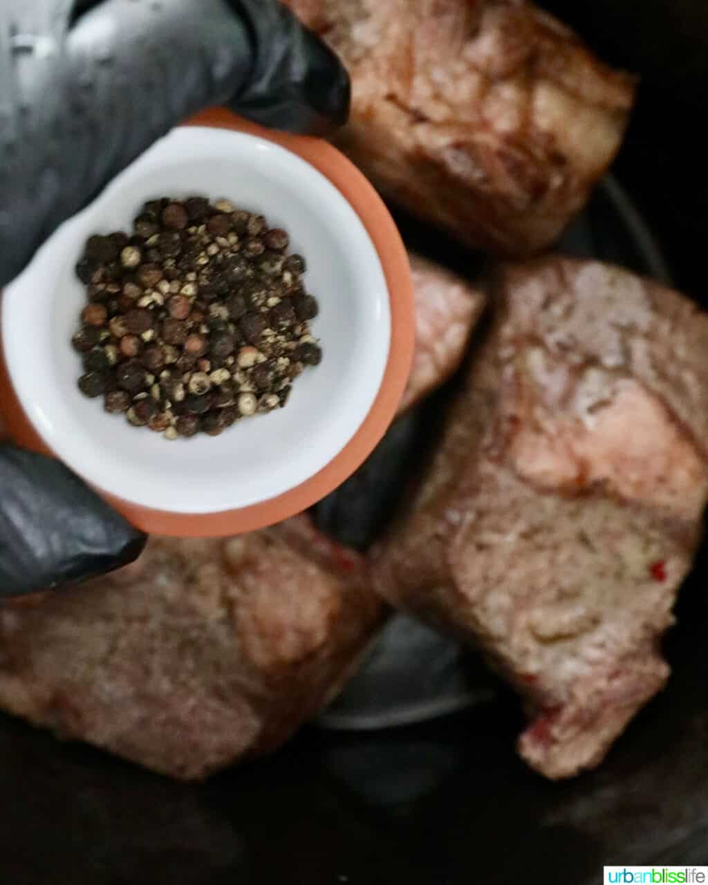 adding peppercorns to beef short ribs in the slow cooker