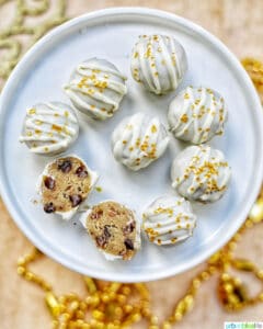 gold decorated white chocolate coated cookie dough truffles on a plate with two split open