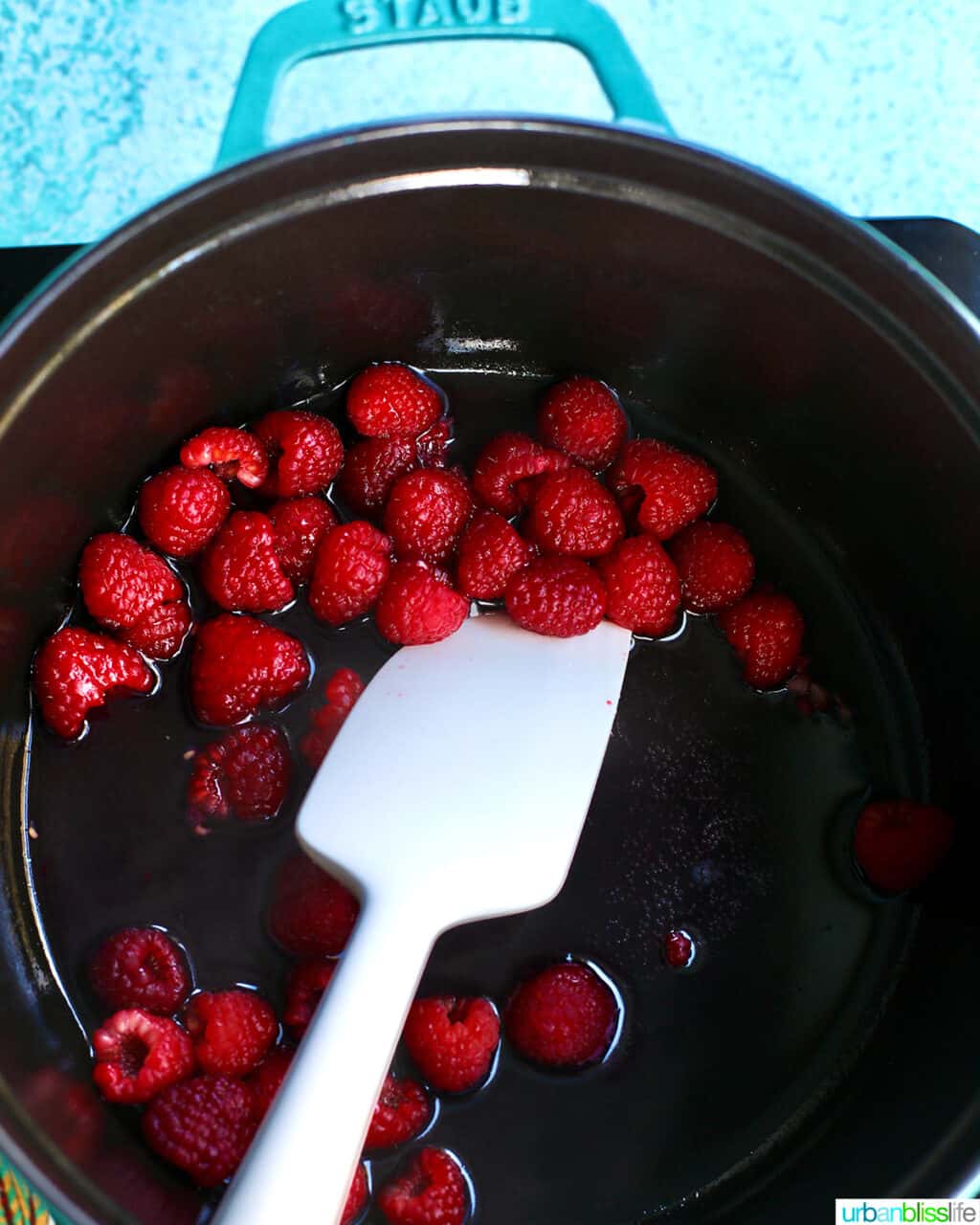 stirring raspberries in a pot to make syrup