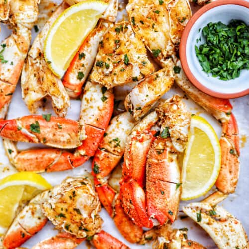air fryer crab legs with lemon wedges and chopped parsley.