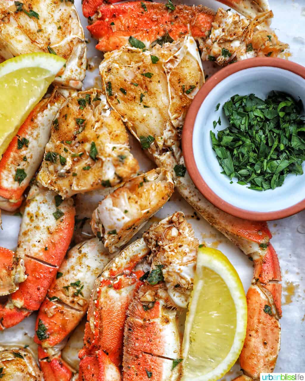 air fryer crab legs with parsley with lemon wedges and chopped parsley.