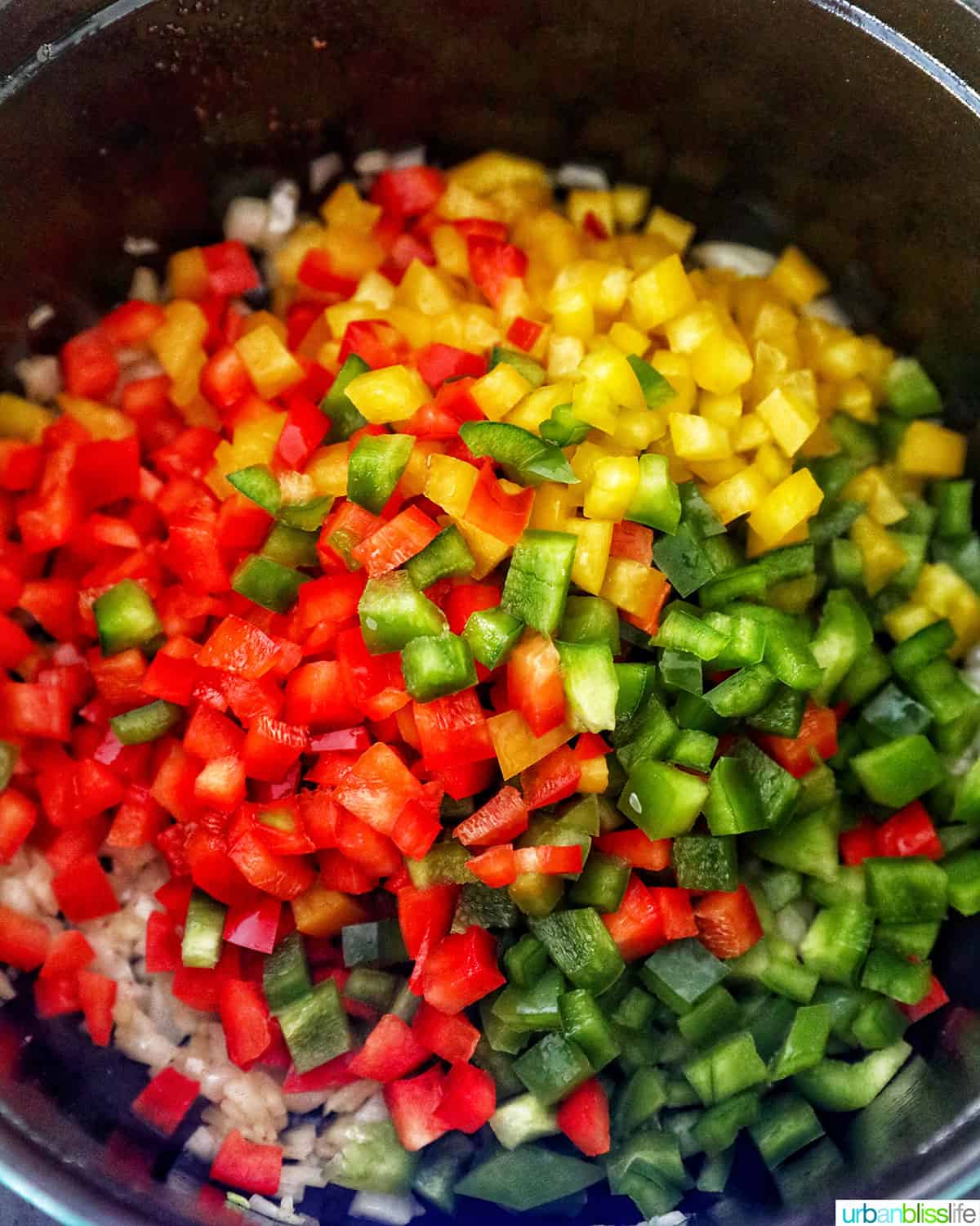 adding red yellow and green peppers to a pot