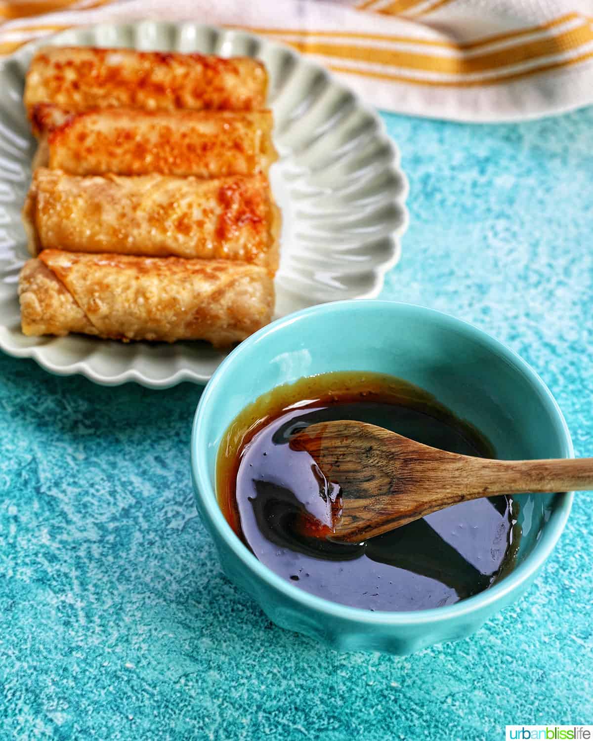 caramel drizzle in a bowl next to plate of Filipino turon banana lumpia