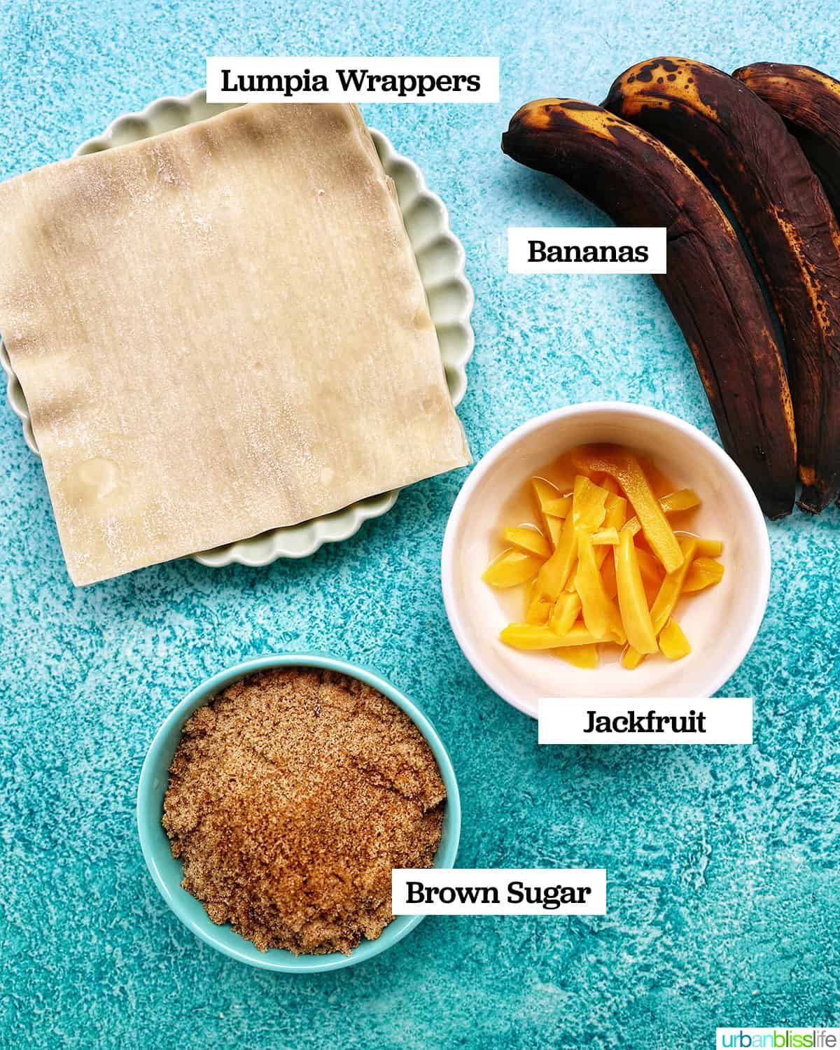 ingredients to make Filipino turon banana lumpia in bowls on a blue background.
