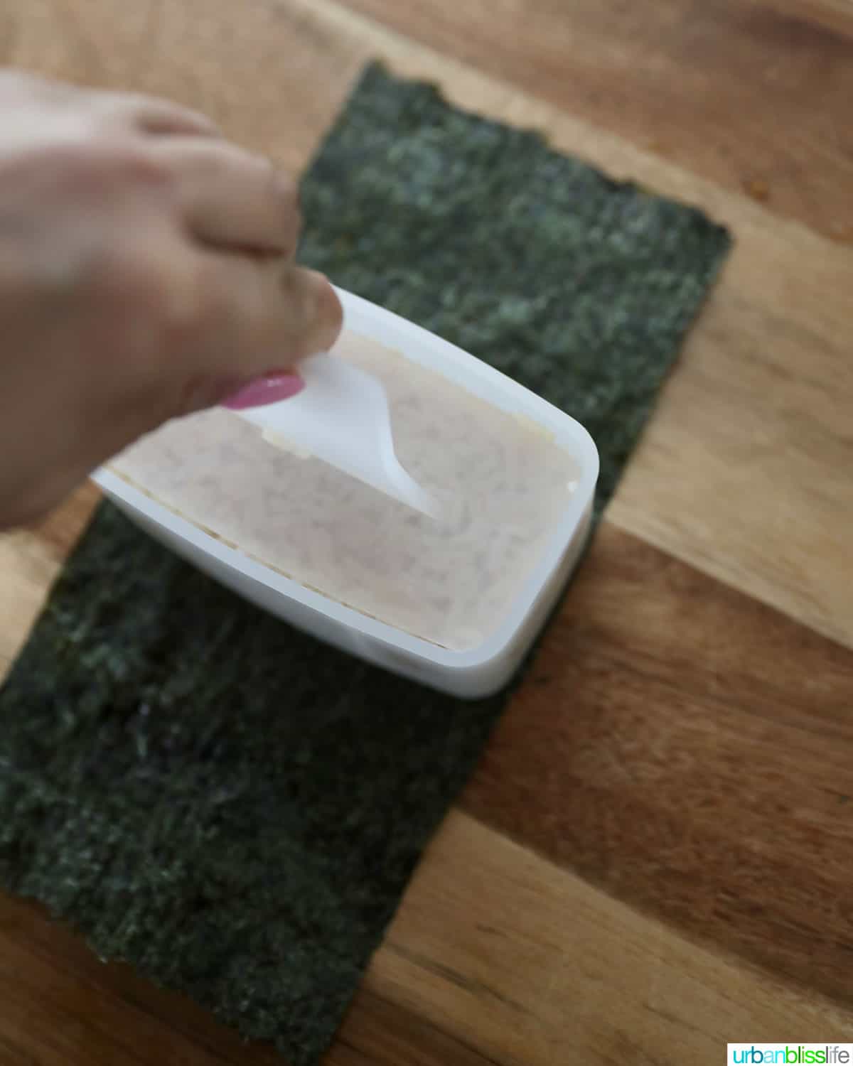 pressing down on the rice in the spam musubi maker