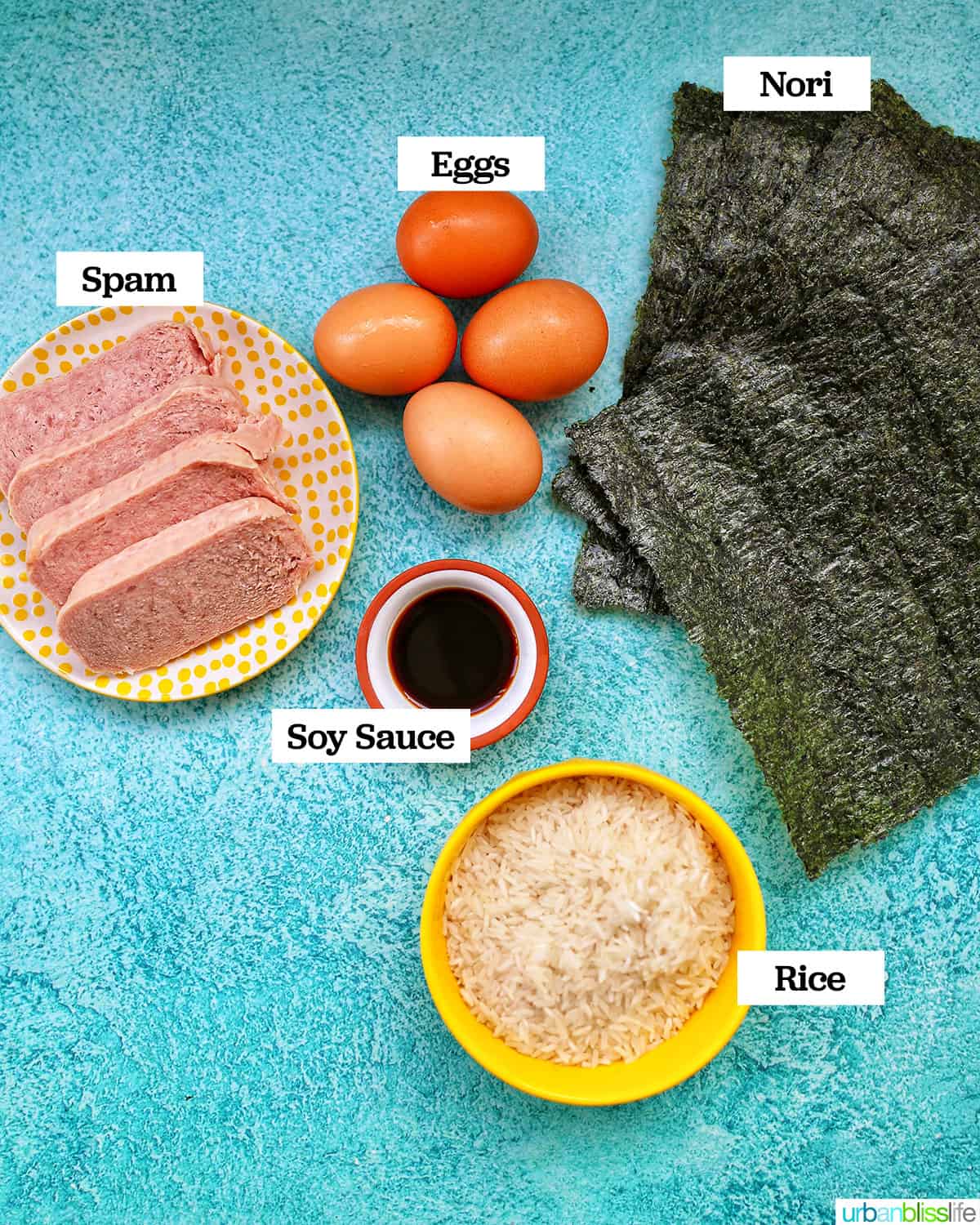 ingredients to make spam musubi with egg on a blue background.