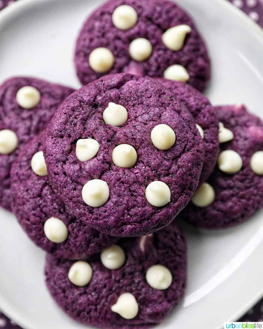 ube white chocolate chip cookies stacked on top of one another on a white plate.