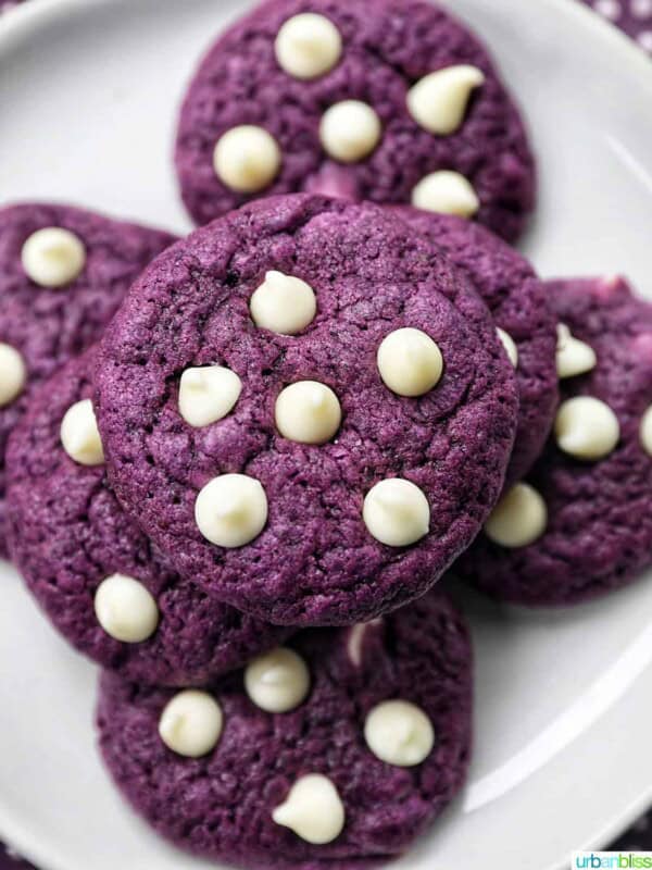 ube white chocolate chip cookies stacked on top of one another on a white plate.