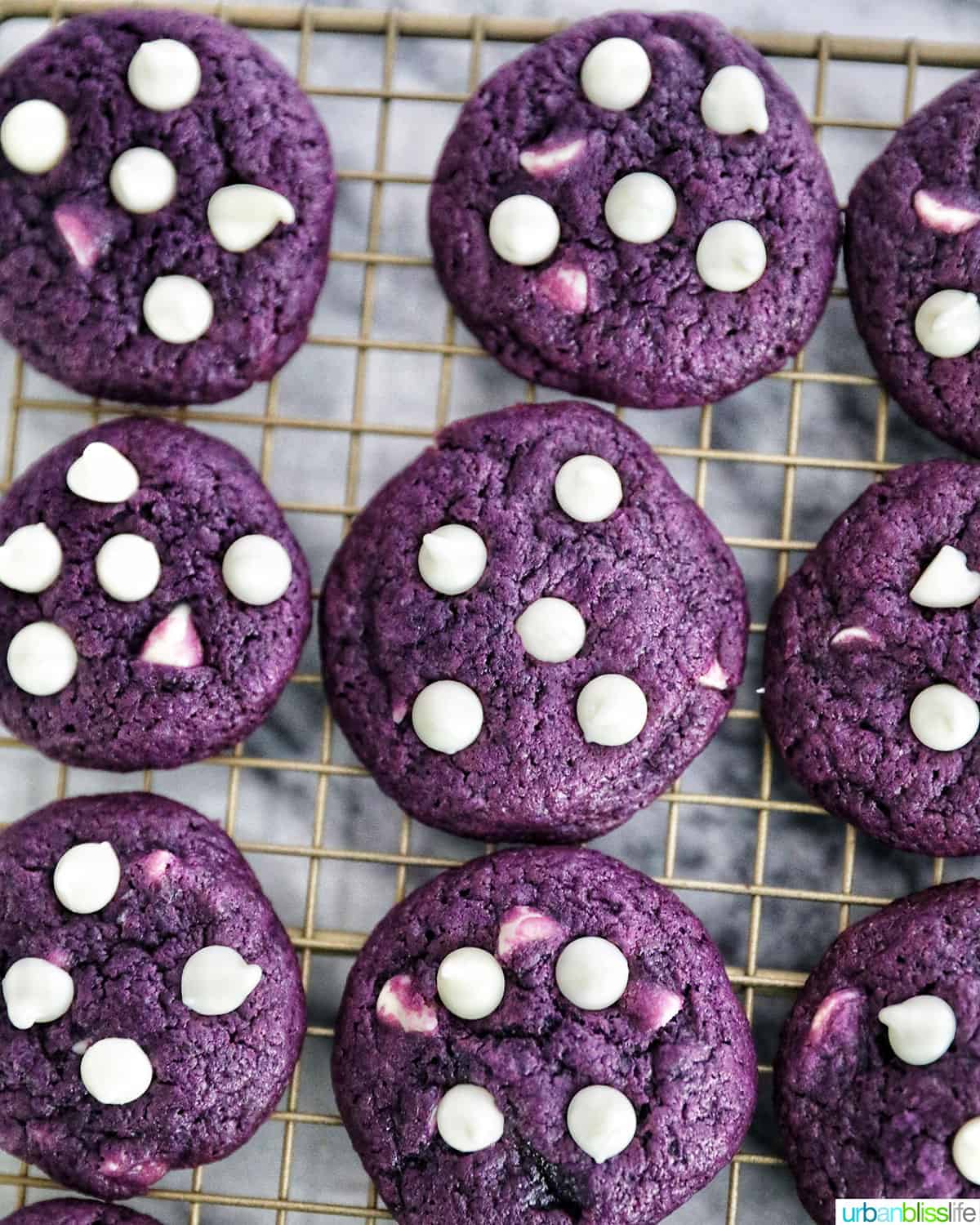 bright purple Ube cookies with white chocolate chips on top of a baking cooling rack on marble table.