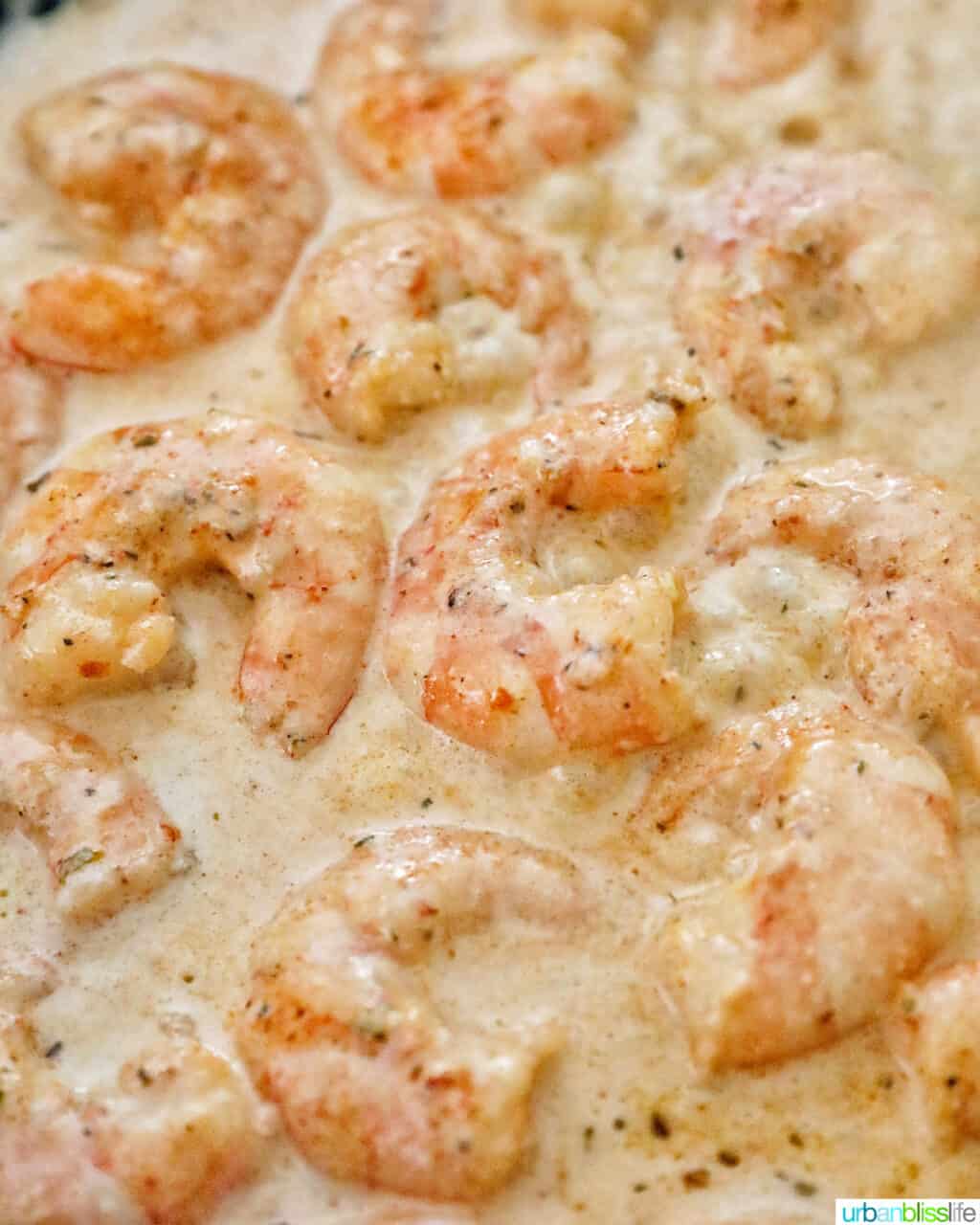 adding cream to the cajun shrimp pasta in the pan