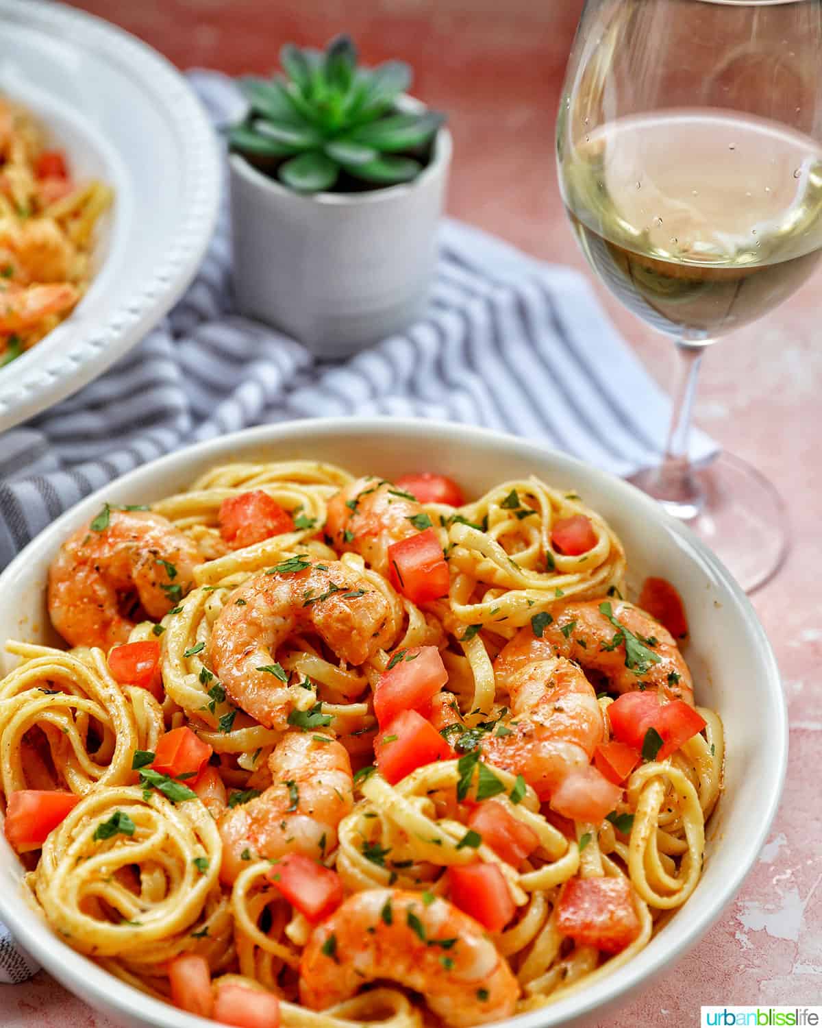 bowls of Cajun Shrimp Pasta with glass of white wine