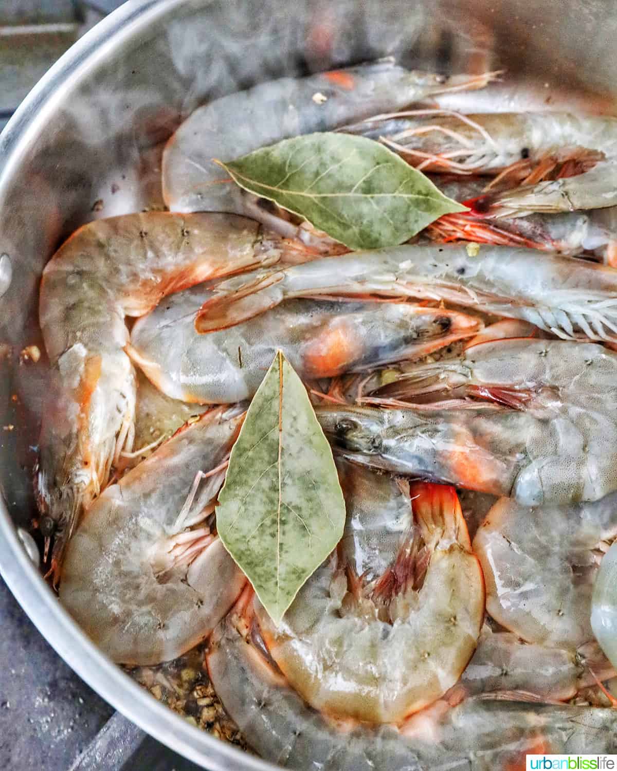 raw shrimp with bay leaves in pan