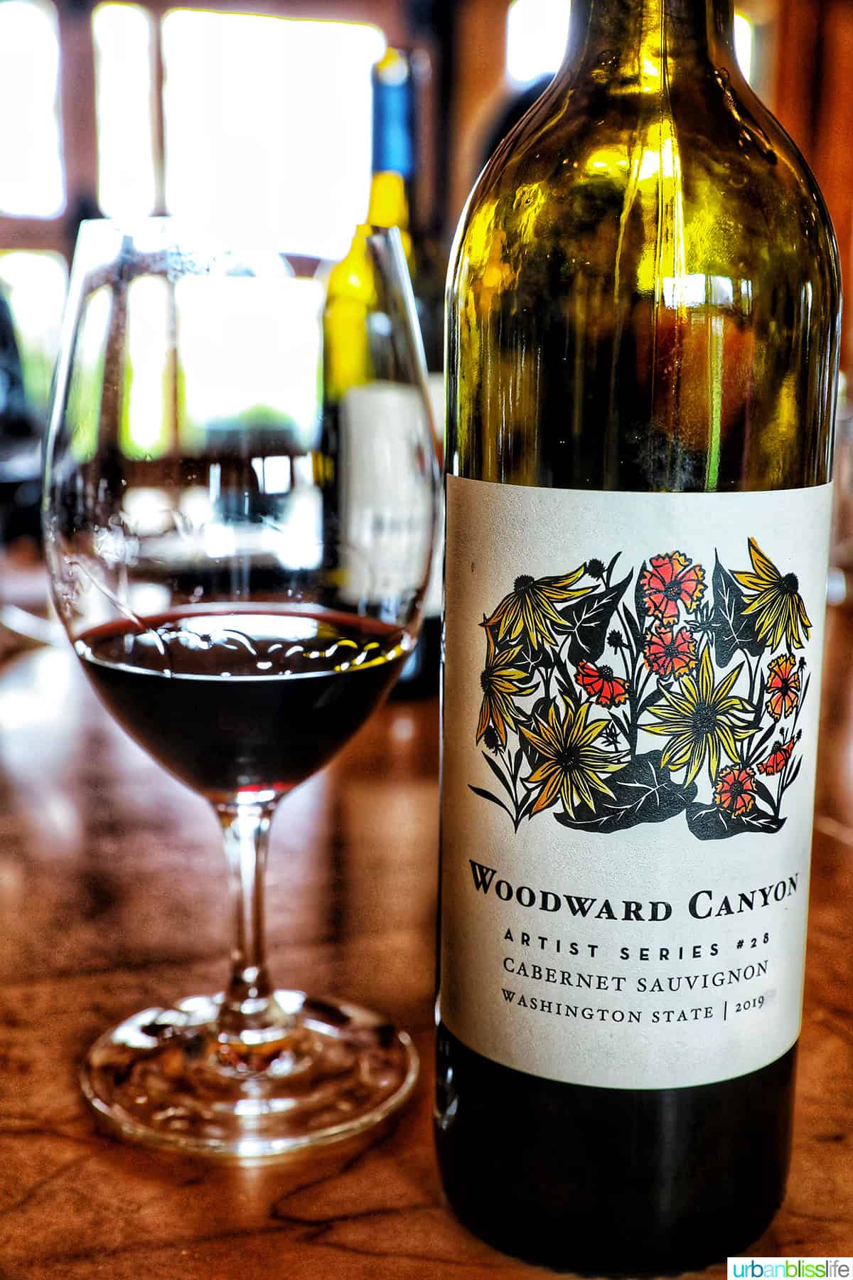 woodward canyon wine bottle next to a glass of cabernet sauvignon.
