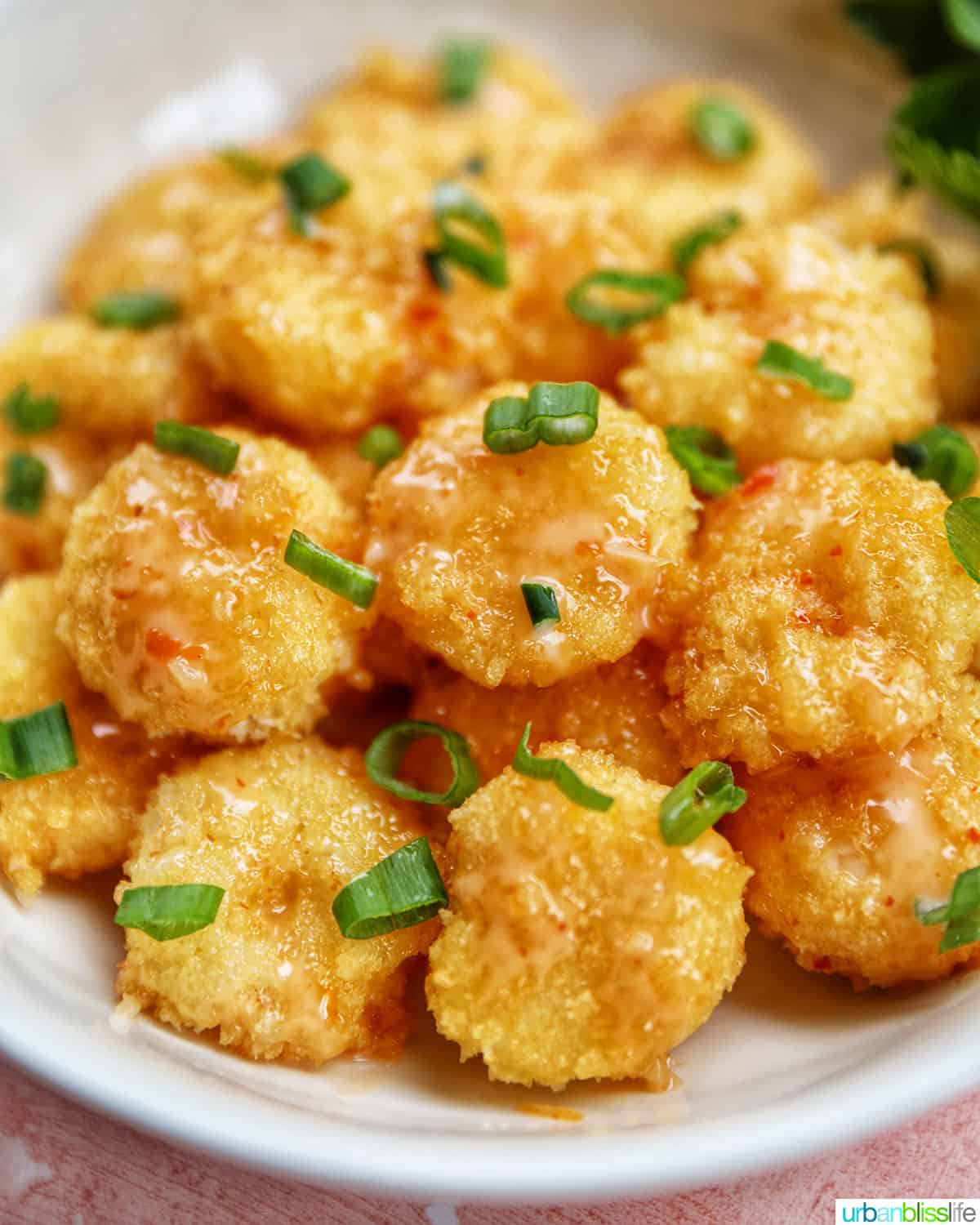 air fryer bang bang shrimp garnished with green onions in a white bowl.