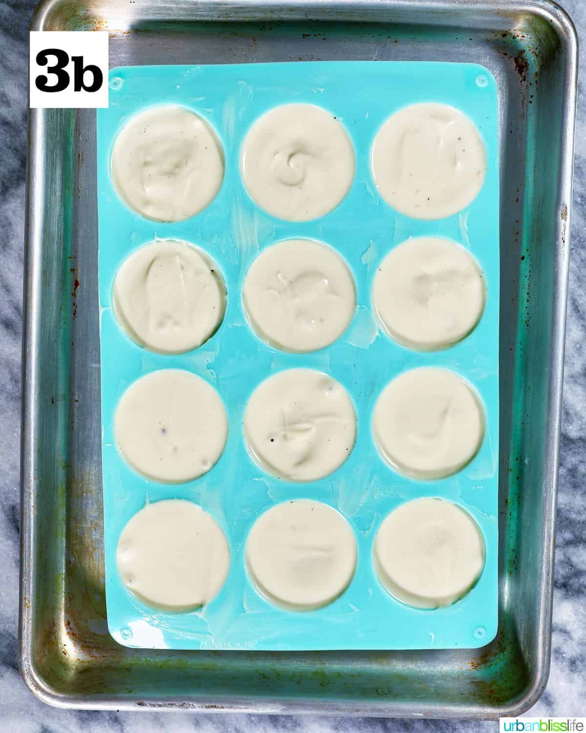 white chocolate covered Oreo cookies in a blue chocolate candy mold on baking sheet.