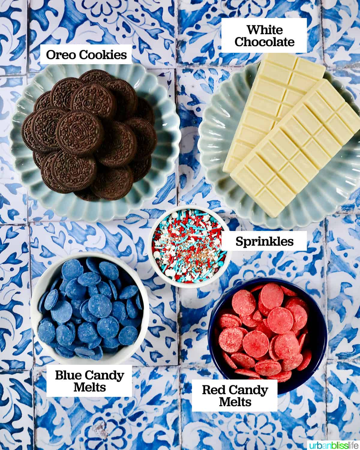 bowls of cookie and chocolate ingredients to make 4th of July chocolate covered Oreos on a blue and white patterned table.
