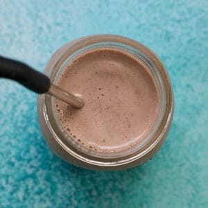 post-workout chocolate protein shake with metal straw.