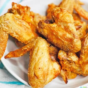 white plate with several crispy air fryer chicken wings on top.