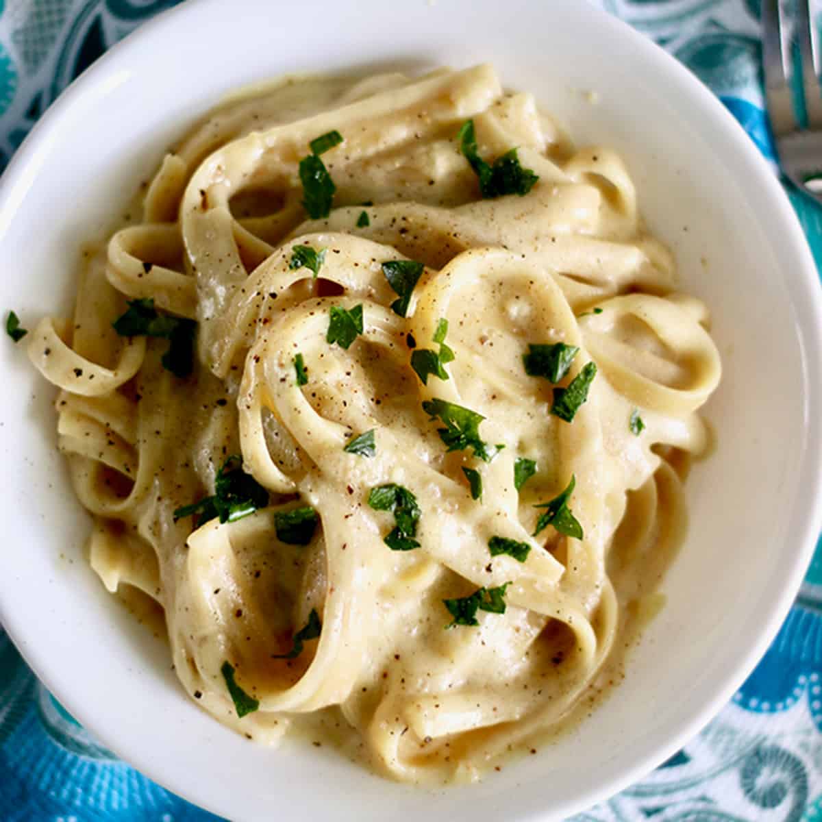 dairy free fettuccine alfredo topped with parsley.