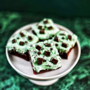 mint chocolate chip brownies on a pedestal plate.