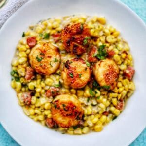 seared scallops with corn in a white bowl.