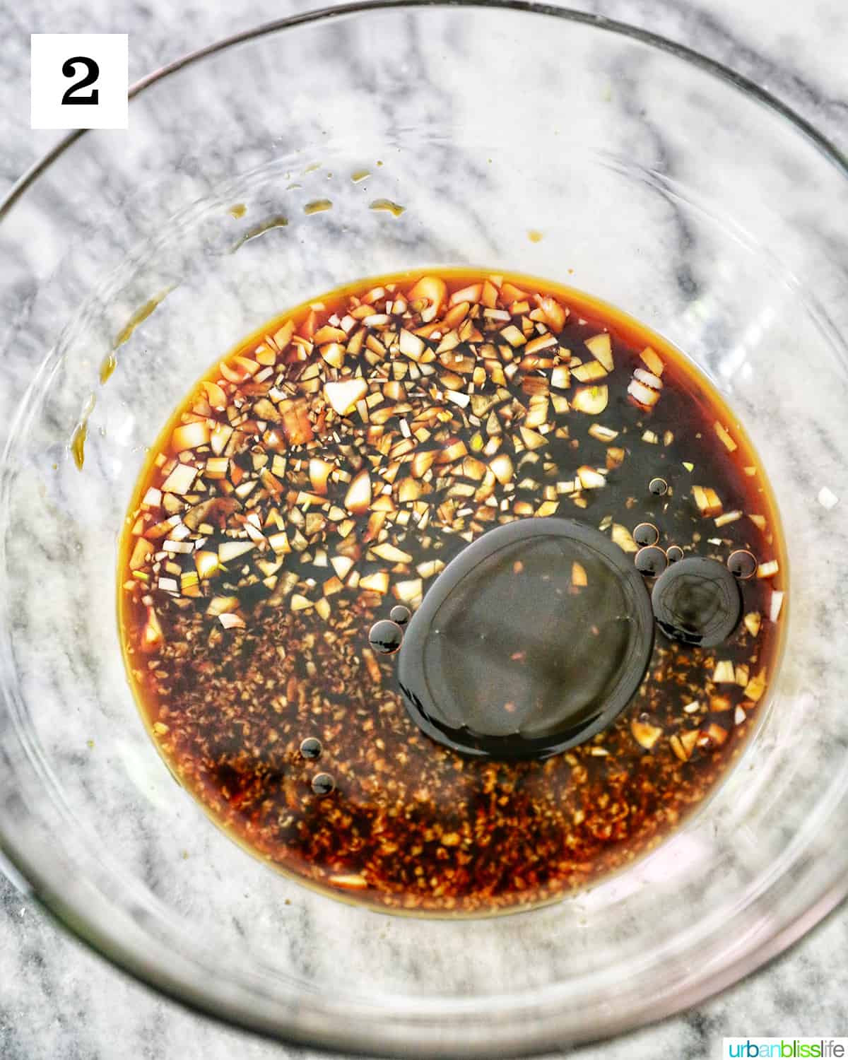 sesame garlic soy sauce in a large clear glass bowl on marble table.