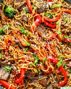 sesame garlic noodles with steak, red bell peppers, broccoli, and carrots.