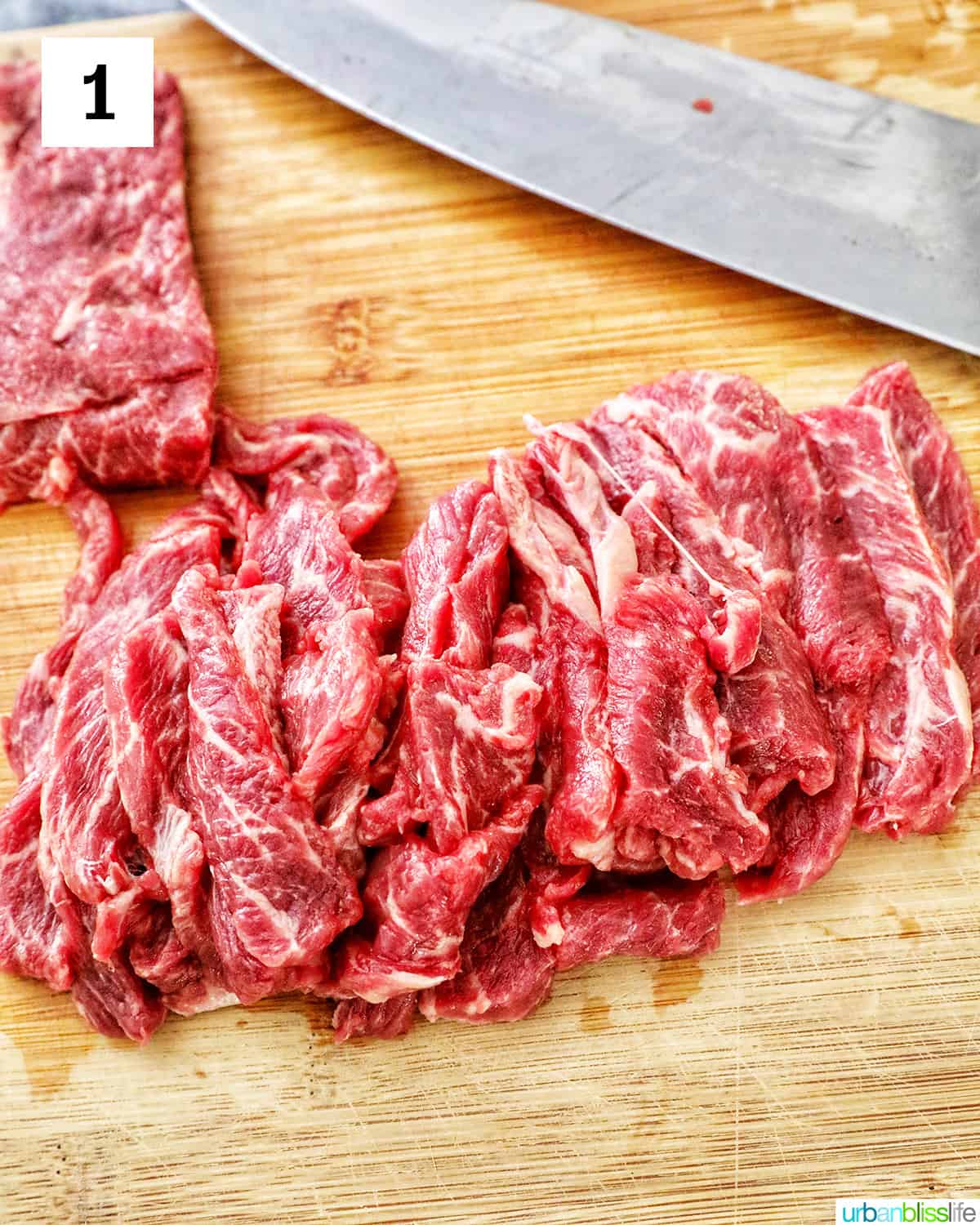 steak sliced thinly on a cutting board with a knife.