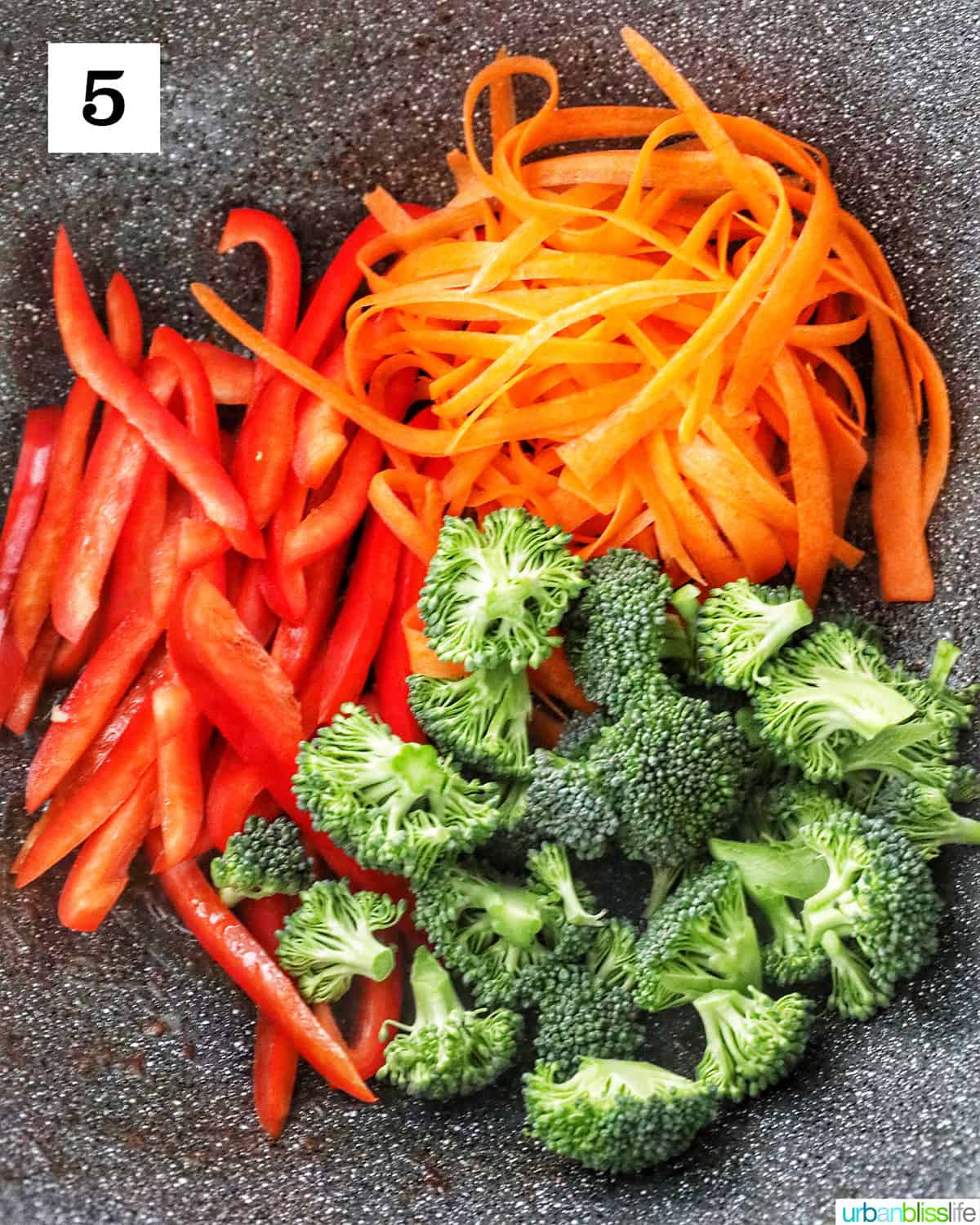 red bell peppers, carrots, and broccoli in a large wok.