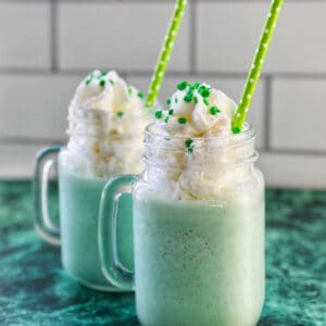 green shamrock shake with whipped cream and green straws.