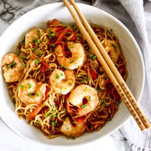 shrimp lo mein in a bowl with chopsticks.