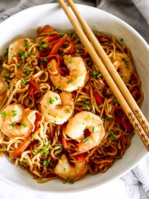 shrimp lo mein in a bowl with chopsticks.