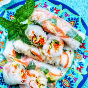summer shrimp salad rolls on a blue patterned plate and peanut sauce.