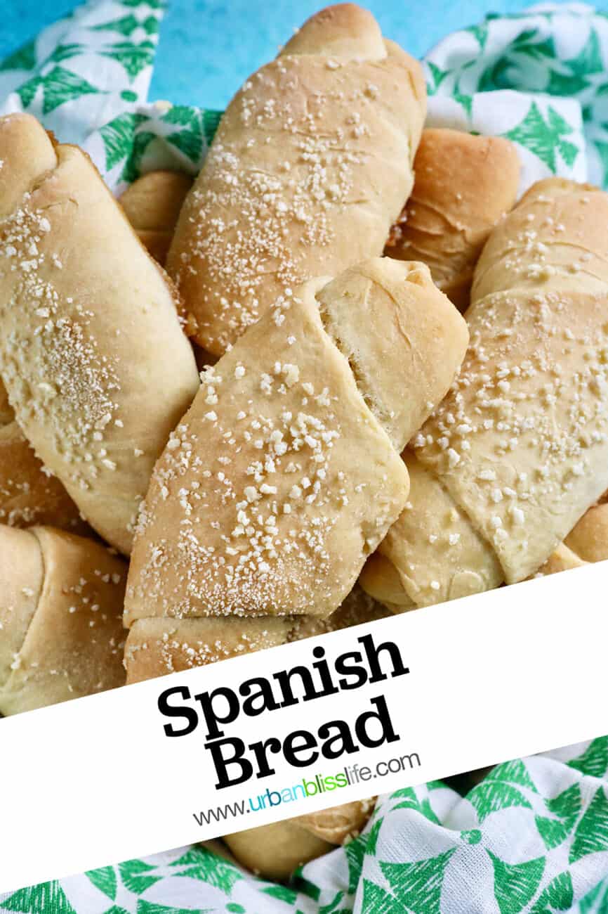 several freshly baked Filipino Spanish bread rolls with breadcrumbs on a green napkin with title text overlay.