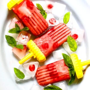 strawberry rhubarb mint popsicles on a white platter.