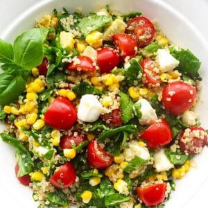 corn and quinoa caprese salad with tomatoes and greens.