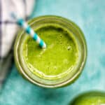 healthy super green smoothie in a glass with blue striped straw.