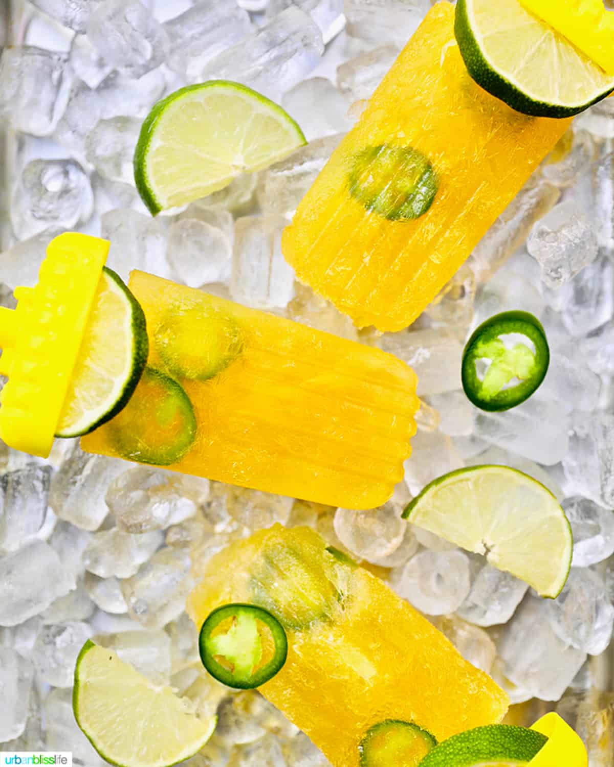 three margarita popsicles over a bed of ice with lime slices and jalapeno slices.