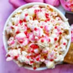 red and pink valentine's day popcorn mix in a white bowl.