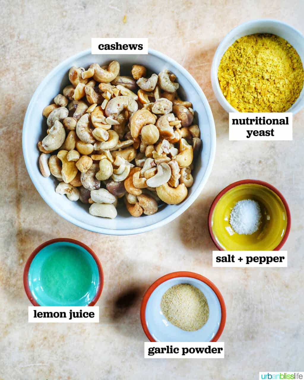 bowls of ingredients with ingredient names to make Vegan Cashew Cheese on a yellow table.