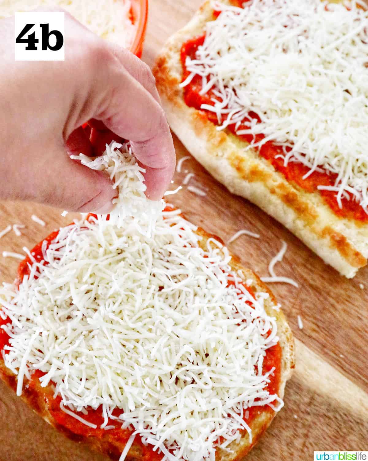 two halves of french bread topped with pizza sauce and cheese on a cutting board.