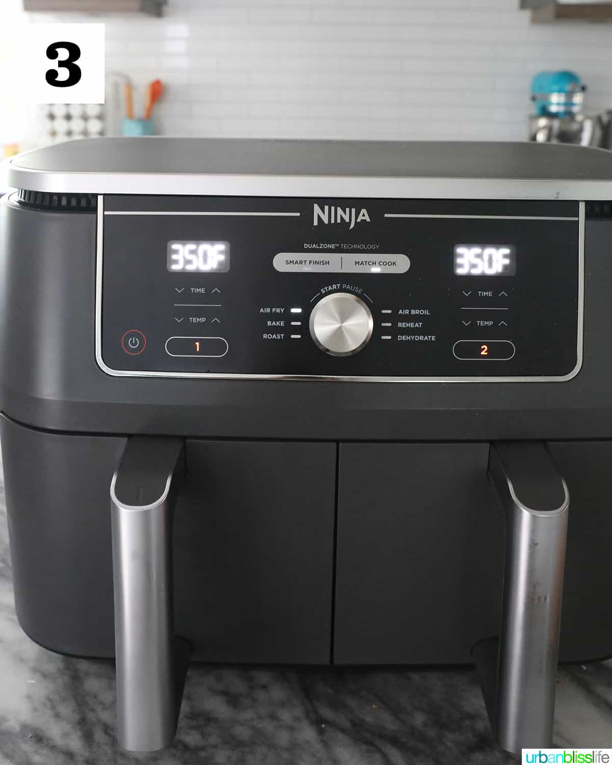 Ninja Foodi dual air fryer set for 350 degrees on a marble countertop.