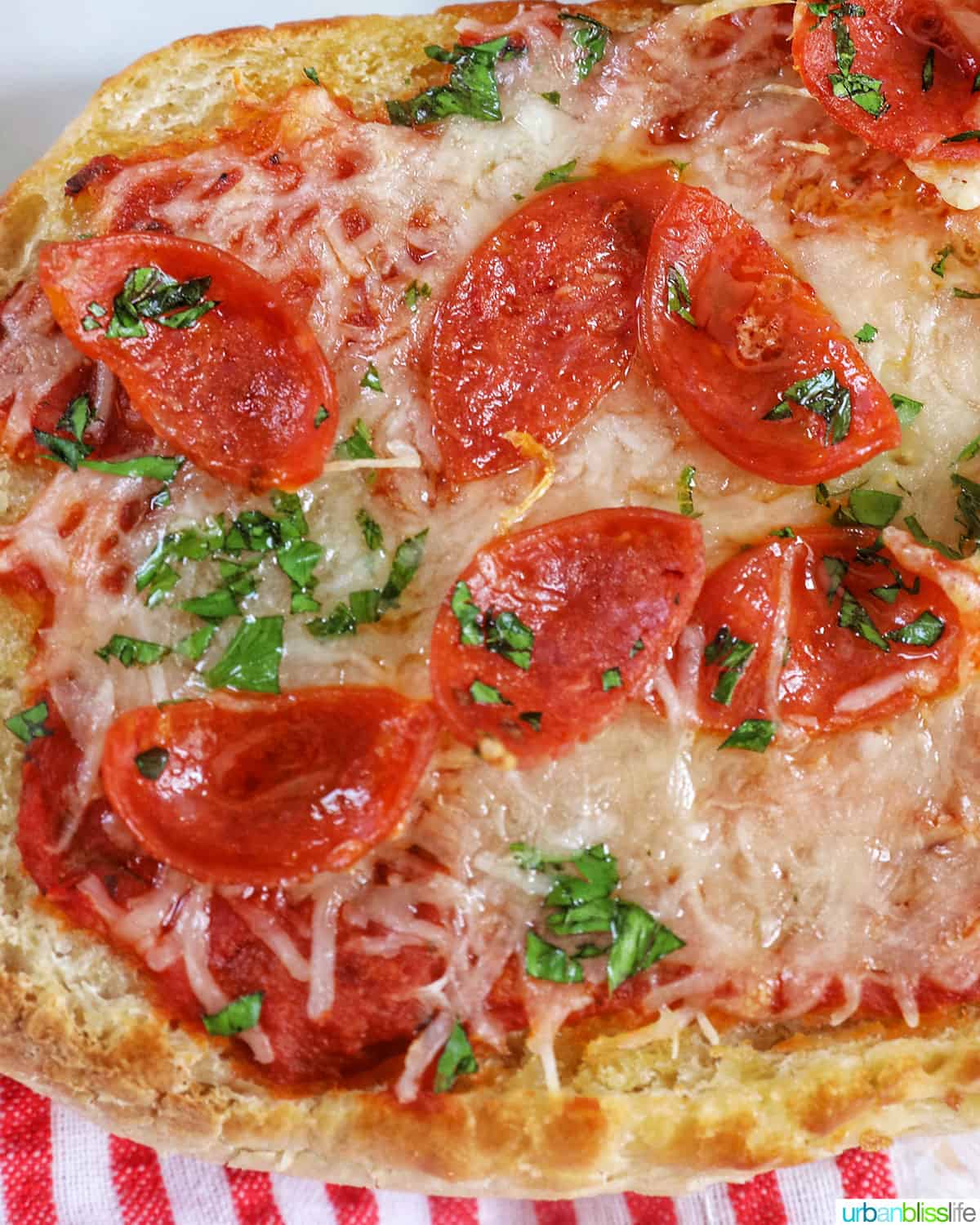 pepperoni french bread pizza with parsley and cheese on a red striped napkin.
