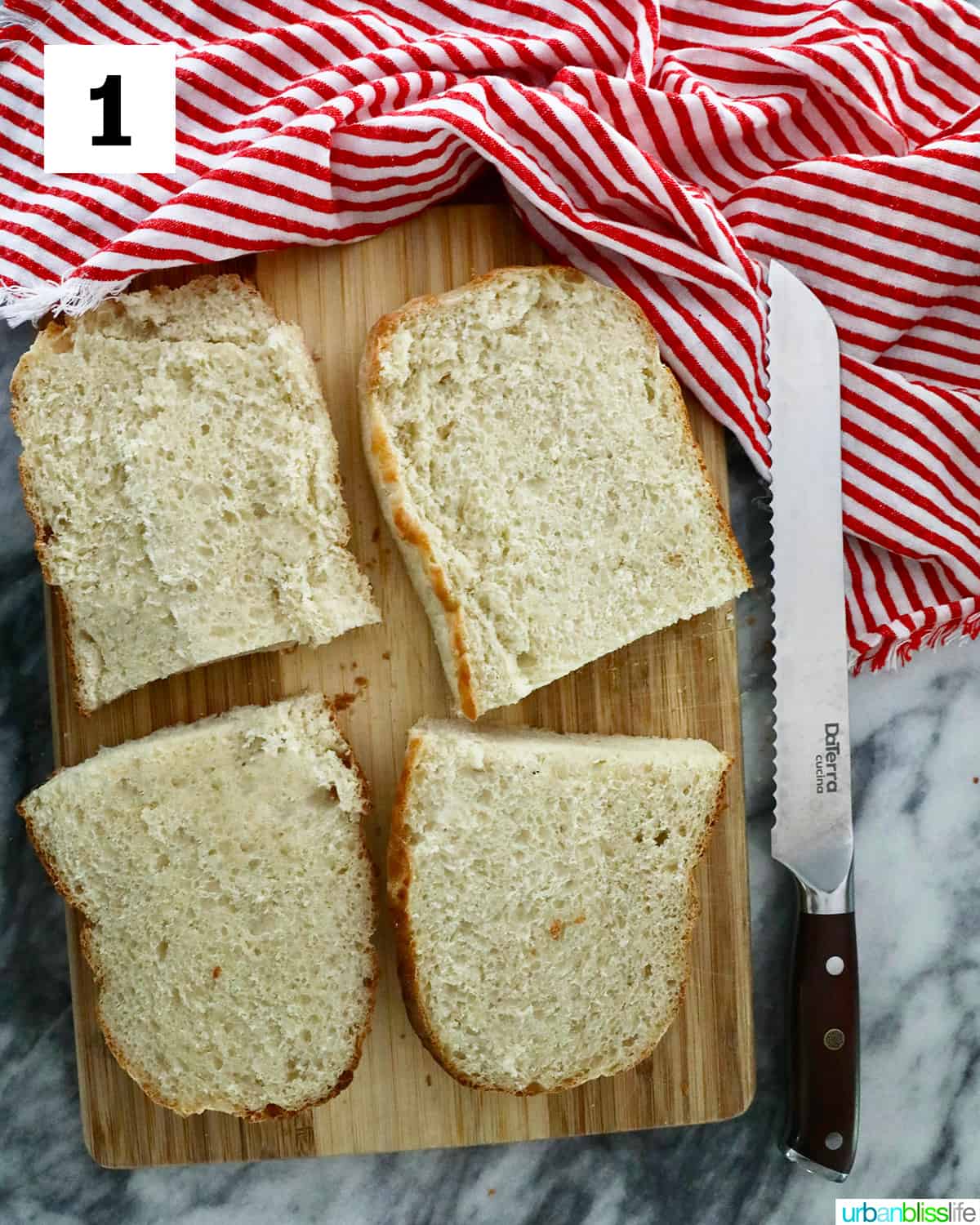 four sliced halves of french bread on a cutting board and red striped napkin with bread knife.