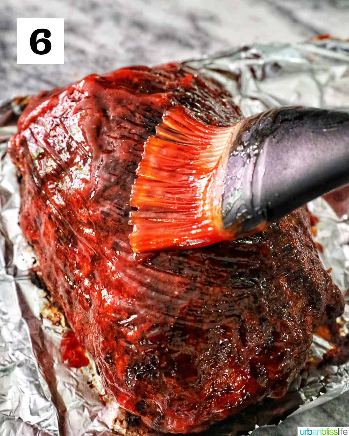 brushing sauce on top of meatloaf on top of foil.