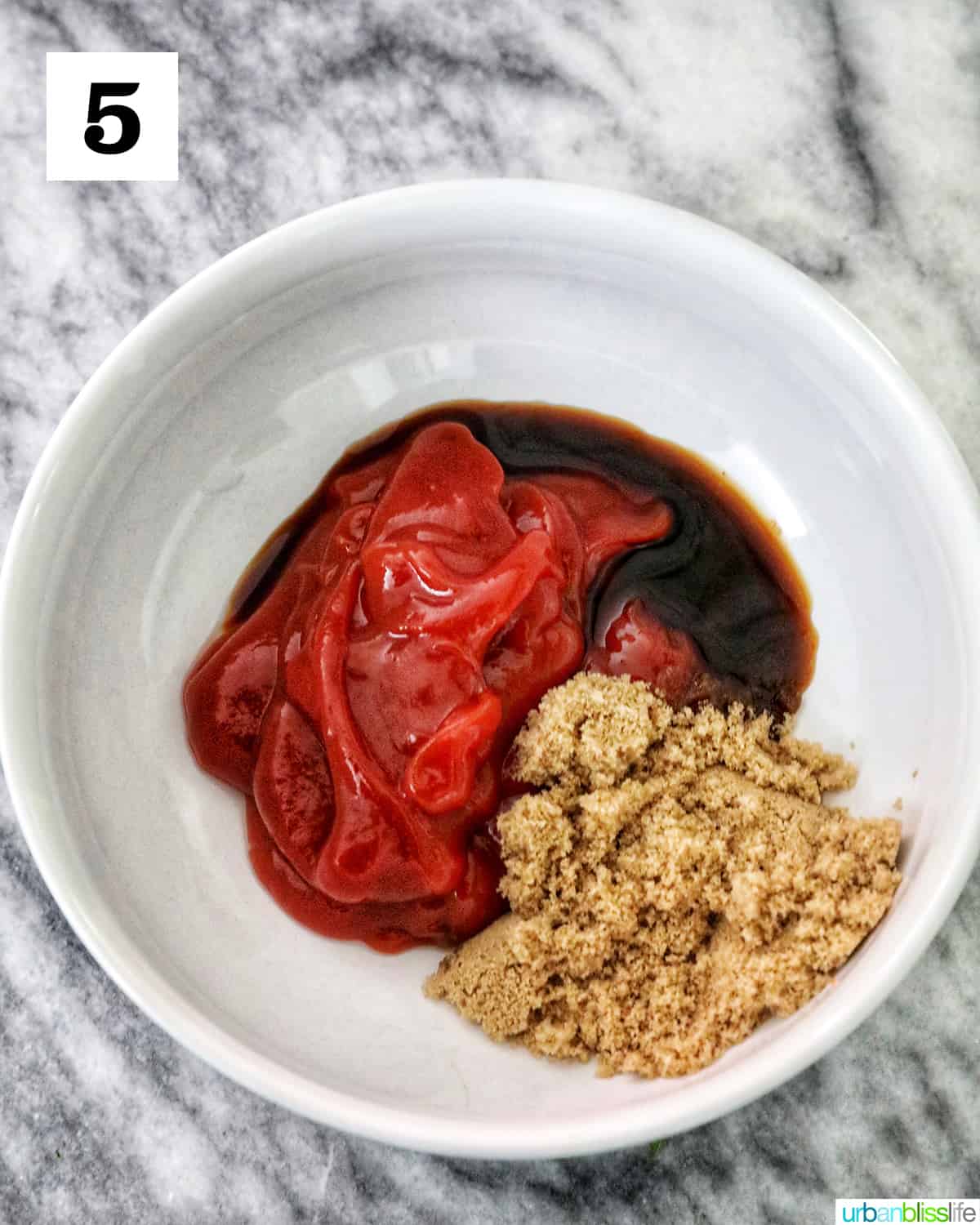 white bowl with ketchup and brown sugar on top of a marble counter.