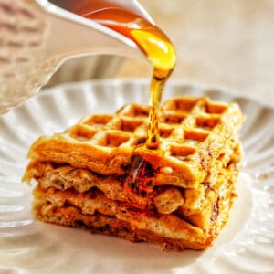 maple syrup pouring over banana chocolate chip waffles.