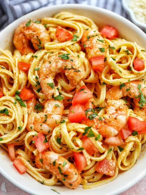 cajun shrimp pasta with herbs in a white bowl.
